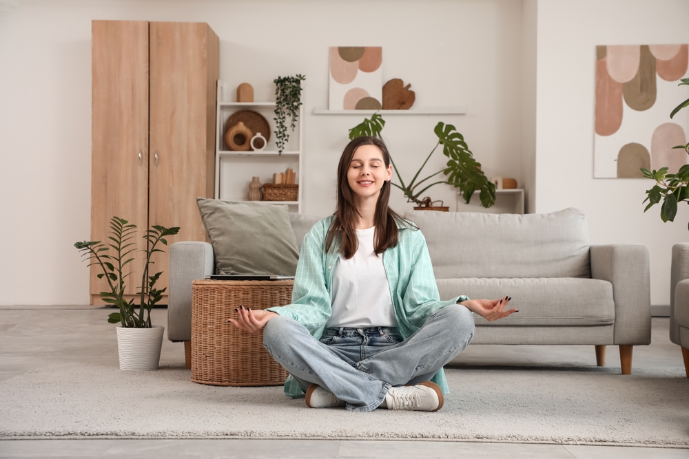 Woman meditating on floor in living room
