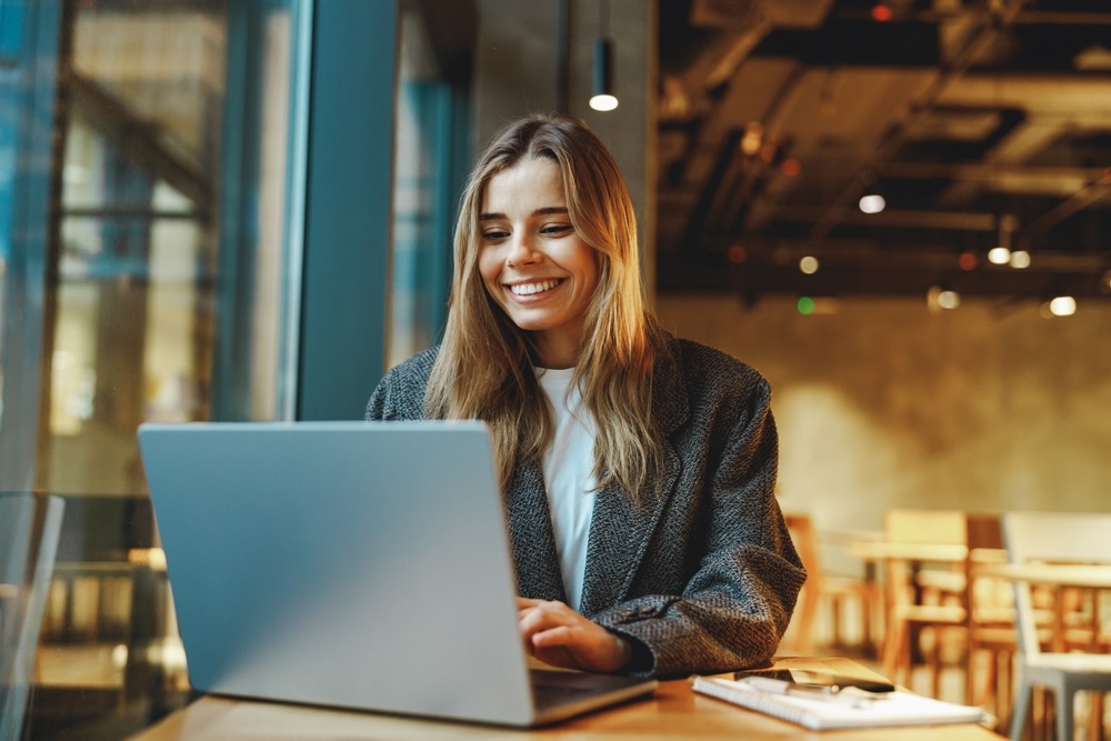Women smiling while using lap sat inside a cafe