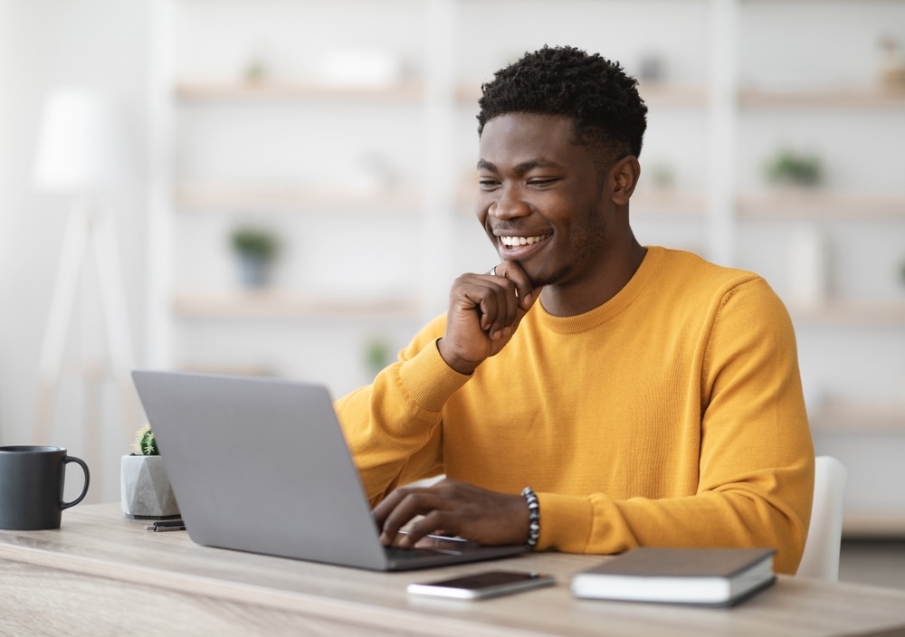 Man wearing yellow jumper while on laptop