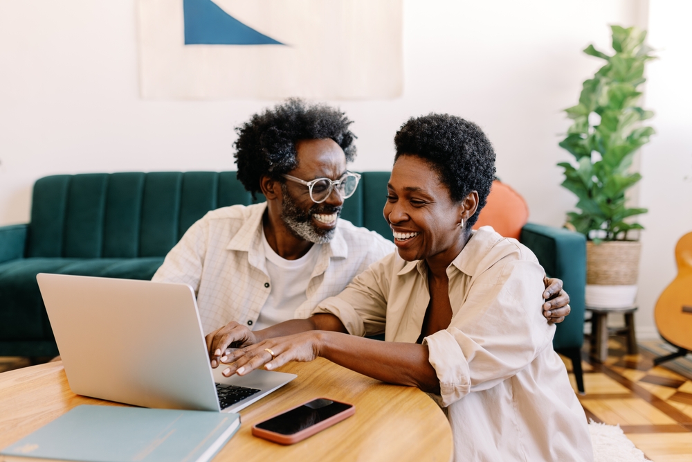 Couple sitting together on their living room floor using a laptop
