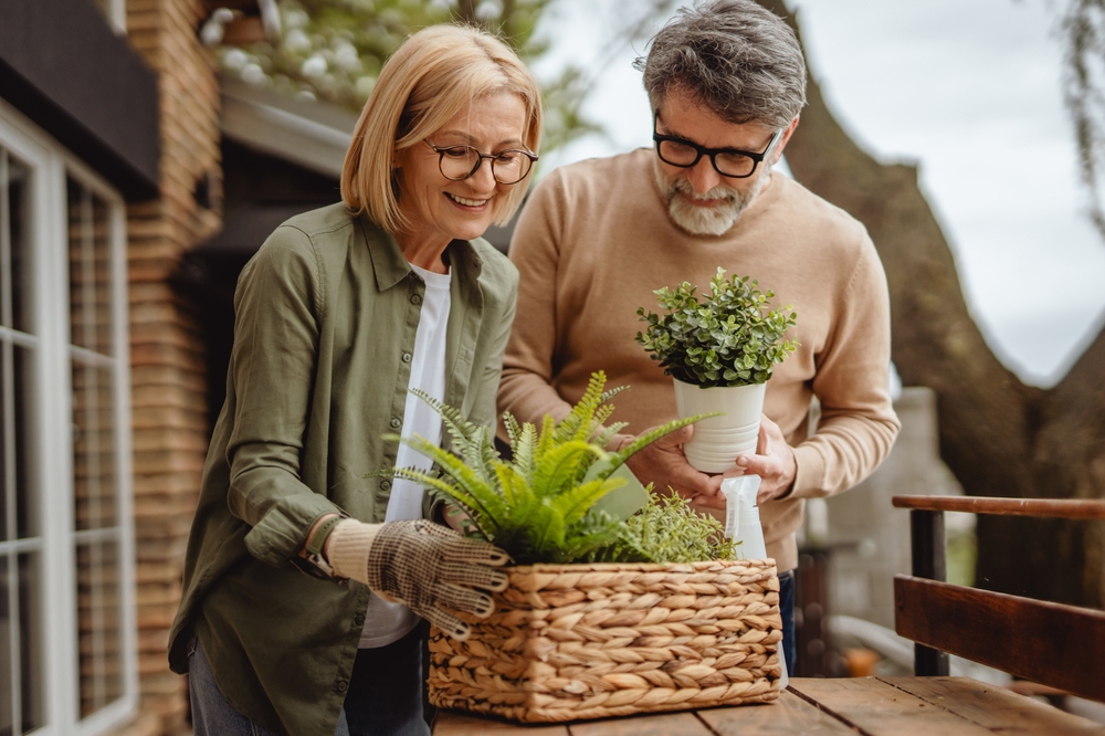 Senior couple arranging potted plants outside