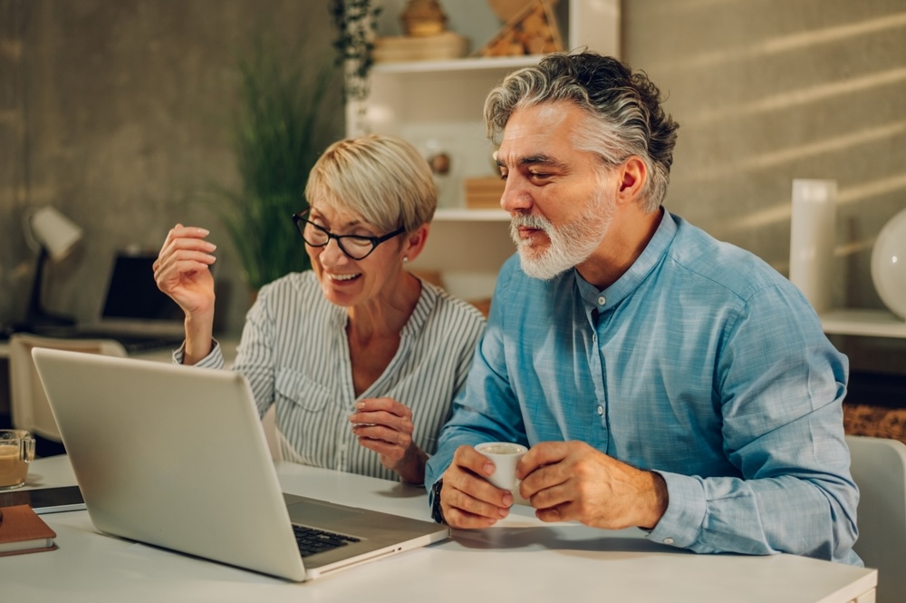 happy senior couple laughing and bonding while using laptop at home