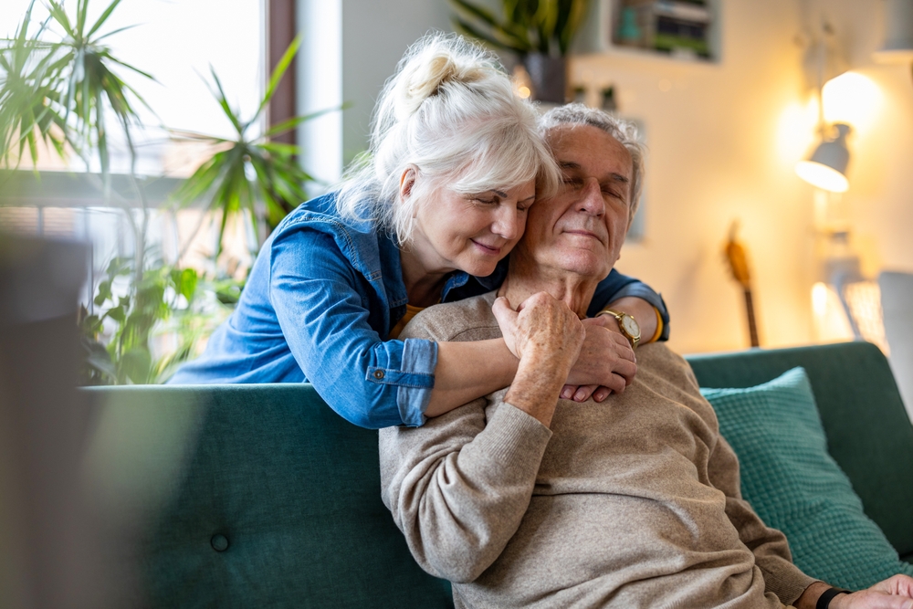happy senior couple sitting on sofa at home