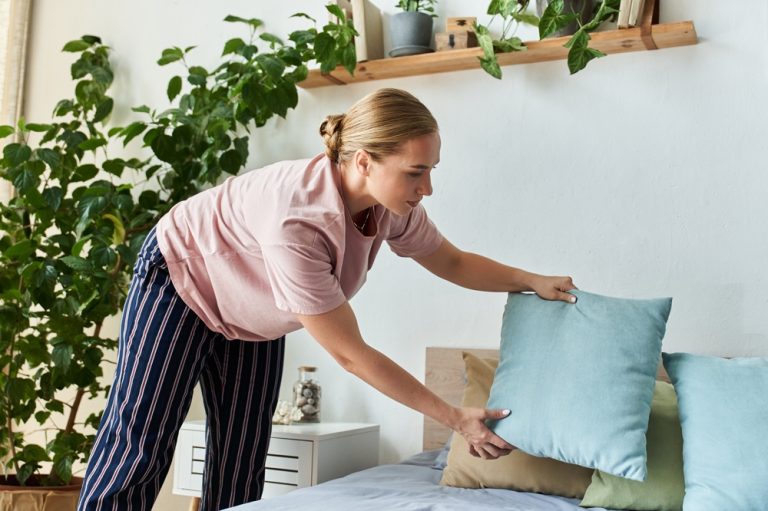 Women arranging bed at home