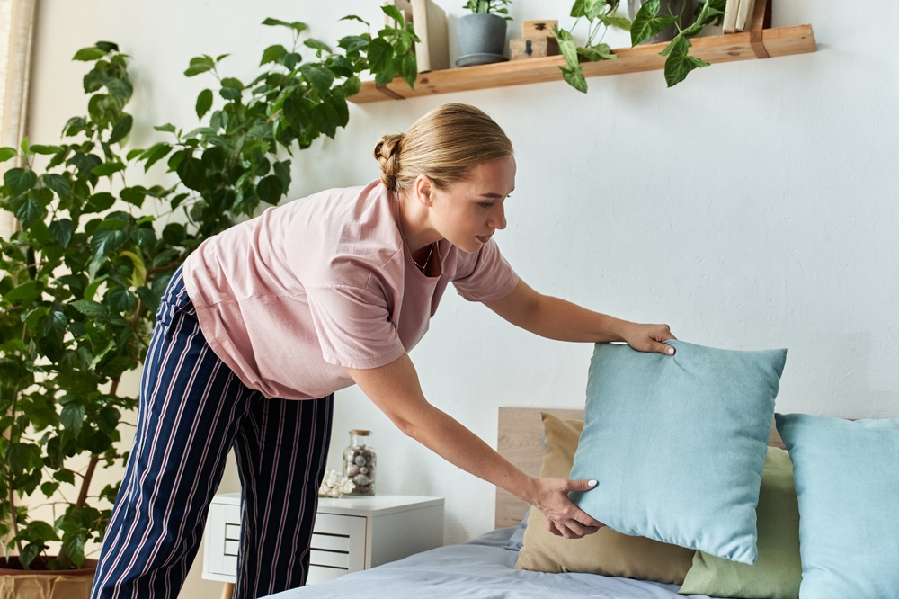 Women arranging bed at home