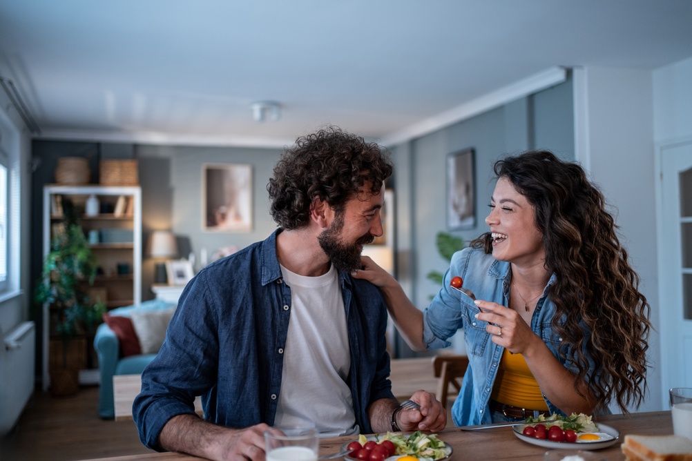 Young couple laughing and eating in their new home
