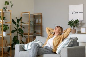 Young woman resting on grey sofa at home