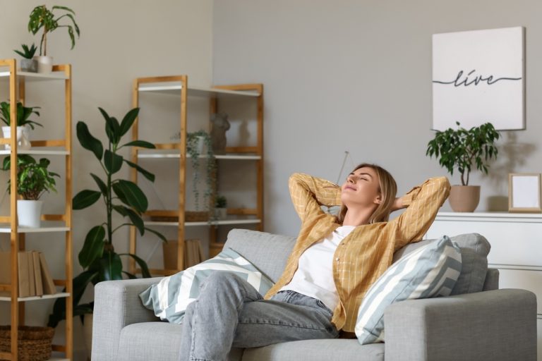 Young woman resting on grey sofa at home