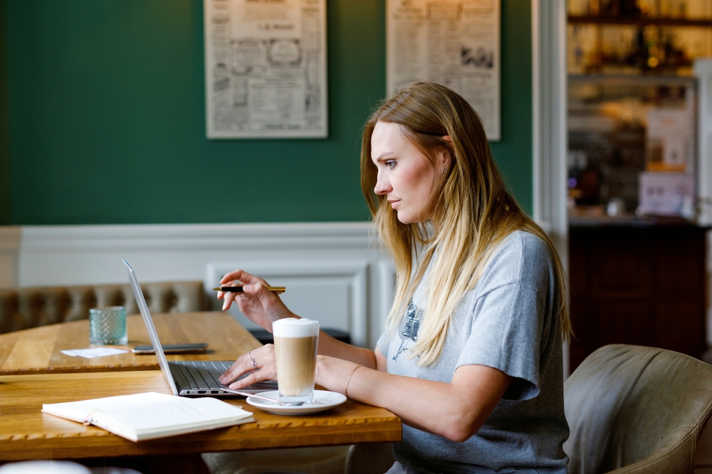 Portrait of young woman using technology of smartphone and looking at laptop reading information on section 24