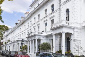 Row of classic white stucco terraced townhouses on a residential street in London.