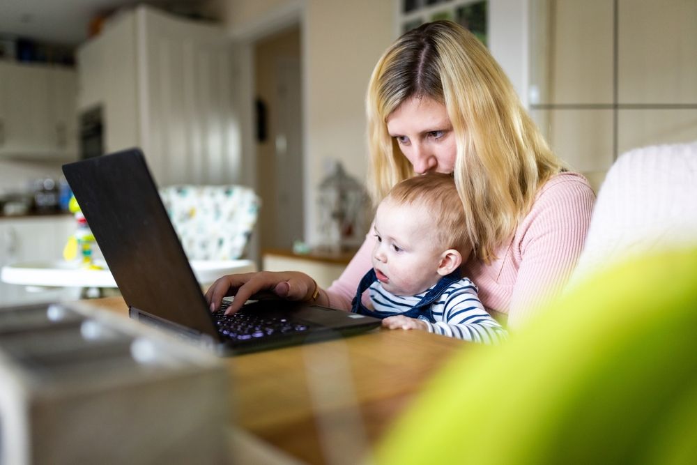 young woman and baby boy looking at computer at home